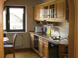 cocina con armarios de madera, fregadero y ventana en Ferienwohnung Lohberg, en Raesfeld