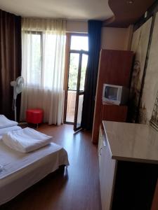 a hotel room with a bed and a tv and a kitchen at Hristovi Apartments & Studios in Pomorie