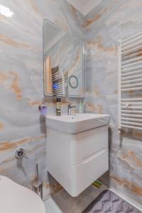 ein Badezimmer mit einem weißen Waschbecken und einem Spiegel in der Unterkunft The Spot - fully equipped, central, modern studio by Flat Mаnager in Sofia + 19 Fotos