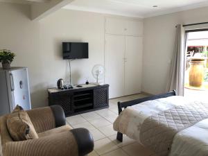 sala de estar con cama, sofá y TV en Big "5" Guesthouse, en Kempton Park