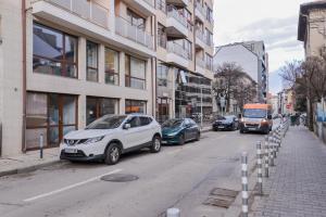 eine Straße mit am Straßenrand geparkten Autos in der Unterkunft The Spot - fully equipped, central, modern studio by Flat Mаnager in Sofia