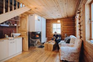 a woman sitting on a couch in a living room with a fireplace at Jaunlidumnieki in Mālpils