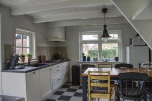 a kitchen with white cabinets and a table with chairs at Huisje de Eersteling in Moddergat