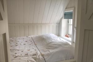 a white bed in a room with a window at Huisje de Eersteling in Moddergat