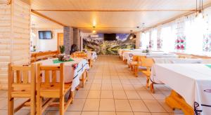 a restaurant with white tables and wooden chairs at Pensjonat Maja in Nowy Sącz