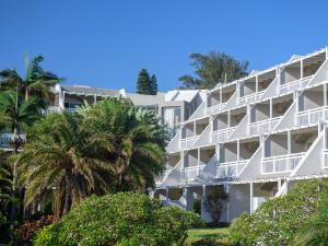 a white building with palm trees in front of it at Umhlanga Cabanas in Durban