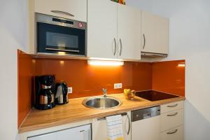 eine Küche mit einer Spüle und einer Mikrowelle in der Unterkunft Aparthotel Alpendiamant Serfaus Wachter GmbH in Serfaus