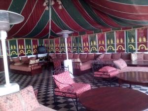 una camera con sedie, tavoli e una tenda di Hotel Riad L' Arganier D' Or ad Aït el Rhazi