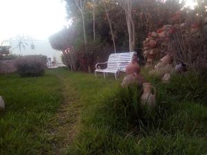a park bench sitting in the grass near a path at Hotel Riad L' Arganier D' Or in Aït el Rhazi