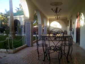 un patio con mesa y sillas en una casa en Hotel Riad L' Arganier D' Or, en Aït el Rhazi