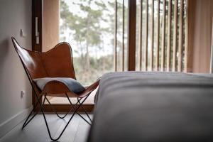 a chair sitting next to a bed in front of a window at Pestana Troia Eco-Resort & Residences in Troia