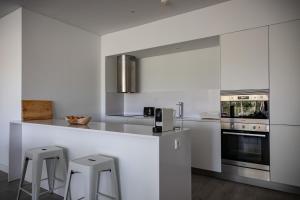 a white kitchen with a counter and stools in it at Pestana Troia Eco-Resort & Residences in Troia