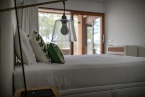 a bed with green and white pillows in a bedroom at Pestana Troia Eco-Resort & Residences in Troia