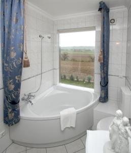 a white bath tub in a bathroom with a window at Landsitz Kapellenhöhe, Hotel Garni in Wiedenbrügge +21 photos