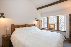 a bedroom with a large white bed and a window at Stunning Blackberry Cottage with Log Burner - located on Haworth Main Street in Haworth