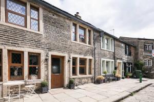 a brick building with a patio in front of it at Stunning Blackberry Cottage with Log Burner - located on Haworth Main Street in Haworth