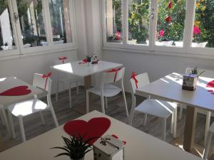 a restaurant with white tables and white chairs and windows at Rione San Carlo in Finale Ligure