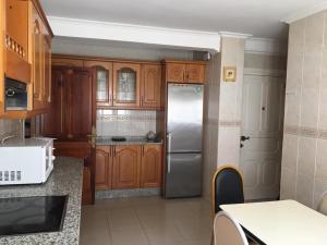 a kitchen with wooden cabinets and a stainless steel refrigerator at Habitaciones El Arco in Zamora