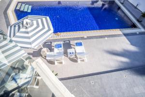 einen Blick über einen Pool mit Sonnenschirmen und Stühlen in der Unterkunft Villa Hibiscus in Protaras