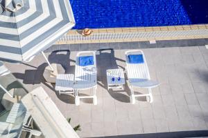 eine Gruppe Stühle und ein Sonnenschirm neben einem Pool in der Unterkunft Villa Hibiscus in Protaras