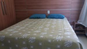 Una cama con dos almohadas azules encima. en Casa Recanto de Guarajuba, en Guarajuba 13 fotos más