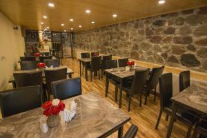a restaurant with tables and chairs and a stone wall at OLYMP in Gudauri