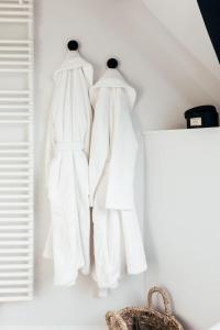 three white clothes hanging on a white wall at Maison Francois in Varsenare