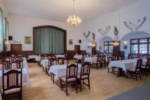 uma sala de jantar com mesas e cadeiras e um lustre em Hotel & Restaurant Lindengarten em Lübben