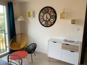 une chambre avec une horloge sur le mur et des chaises dans l'établissement T3 Duplex tout confort - piscine - proche plage - 6 personnes, à Palasca 26 autres photos