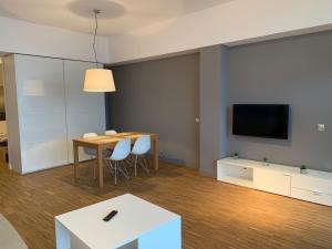 uma sala de estar com uma mesa e uma televisão em Apartament na Klifie DUNE em Ustronie Morskie