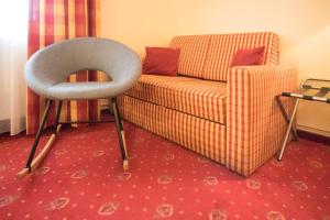 a chair sitting next to a couch and a table at Wirtshaus Restaurant Pension Steirerland in Mureck