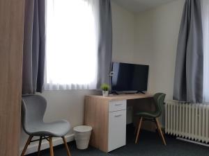 a room with a desk with a television and two chairs at Hotel Silbertanne in Hohegeiß
