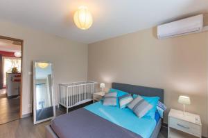 1 dormitorio con cama azul y espejo en La Kaz à l'Étang - Votre Location de Vacances à l'Île de La Réunion en Saint-Louis