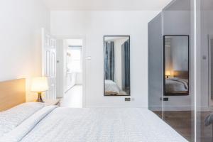 a white bedroom with a bed and two mirrors at Live like a Londoner by TOWER BRIDGE in London