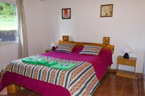 a bedroom with a bed with green slippers on it at Rincón del Sol in Parque Nacional Los Alerces
