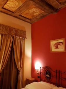 a bedroom with red walls and a bed with a canopy at Albergo delle Drapperie in Bologna