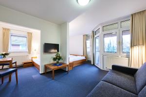 a hotel room with a couch and a bed and windows at Krelinger Freizeit- und Tagungszentrum in Walsrode