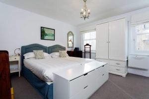 een slaapkamer met een groot bed met een blauw hoofdeinde bij Veeve - A Kensington Mews in Londen