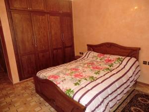 a bed in a bedroom with a wooden cabinet at B205 LOT AL WIFAQ Bensergao AGADIR in Agadir