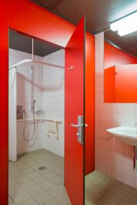 a bathroom with red walls and a shower and a sink at Pontresina Youth Hostel in Pontresina