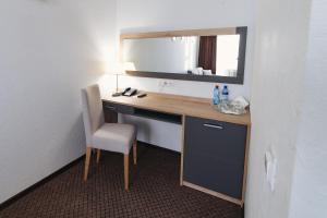 a room with a desk with a mirror and a chair at IzhHotel in Izhevsk