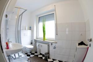 ein Bad mit einem Waschbecken, einem WC und einem Fenster in der Unterkunft City Center Apartments in Nürnberg