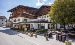 ein Gebäude mit Tischen und Stühlen davor in der Unterkunft SCOL Sporthotel Zillertal in Fügen