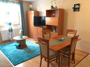 una sala da pranzo con tavolo, sedie e TV di Orchidea Apartman a Hegykő