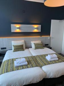 een slaapkamer met 2 bedden en handdoeken bij Hotel & Appartementen Royal in Sas van Gent