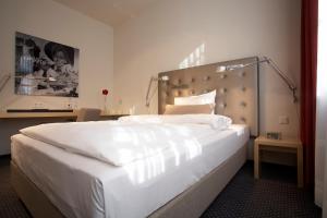 a bedroom with a large white bed with a large headboard at Hotel Maximilians in Essen