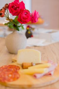 uma mesa com um prato de queijo e um vaso com rosas em B&B Toma' em Pagliare