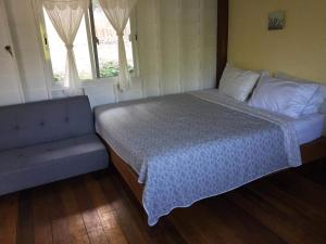 a bedroom with a bed and a couch and windows at The Best Bungalow in Ban Bang Chak