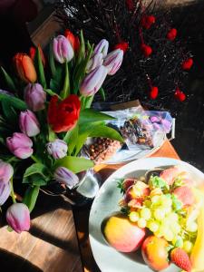 una mesa con un plato de fruta y un jarrón de flores en B&B Aux Quatre Bonniers, en Olne