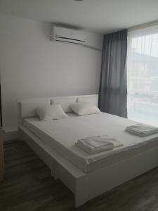 1 cama blanca con 2 almohadas y ventana en Blue Bay Palace Apart Complex, en Pomorie